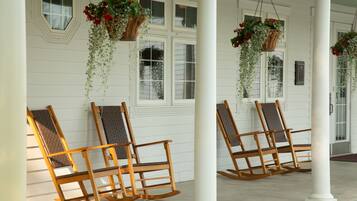 A porch with two rocking chairs and hanging flower baskets.