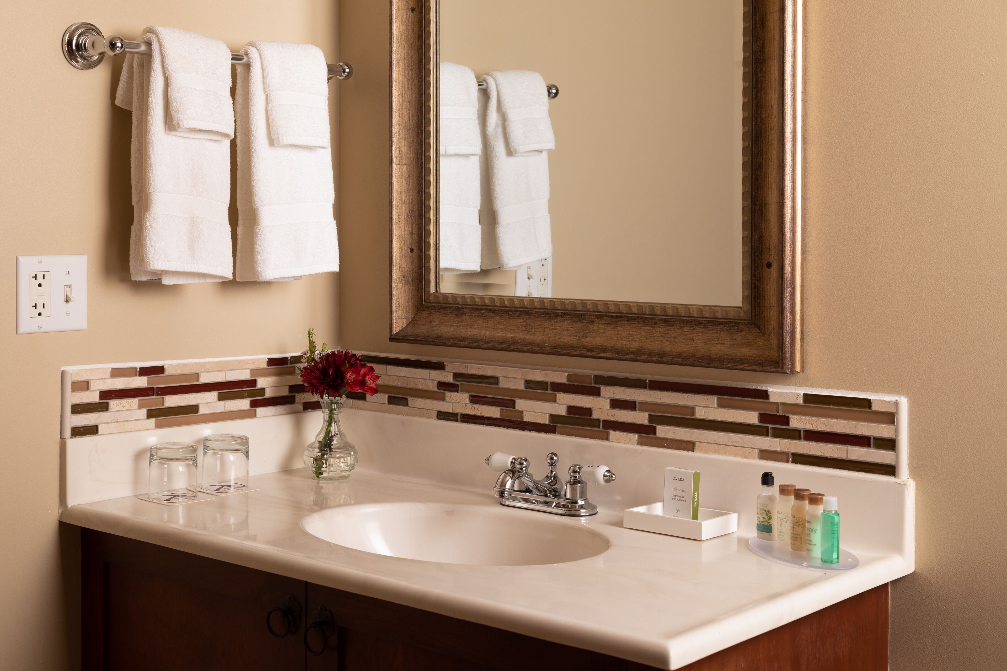 Un bagno con lavandino, specchio, asciugamani e articoli da toilette.