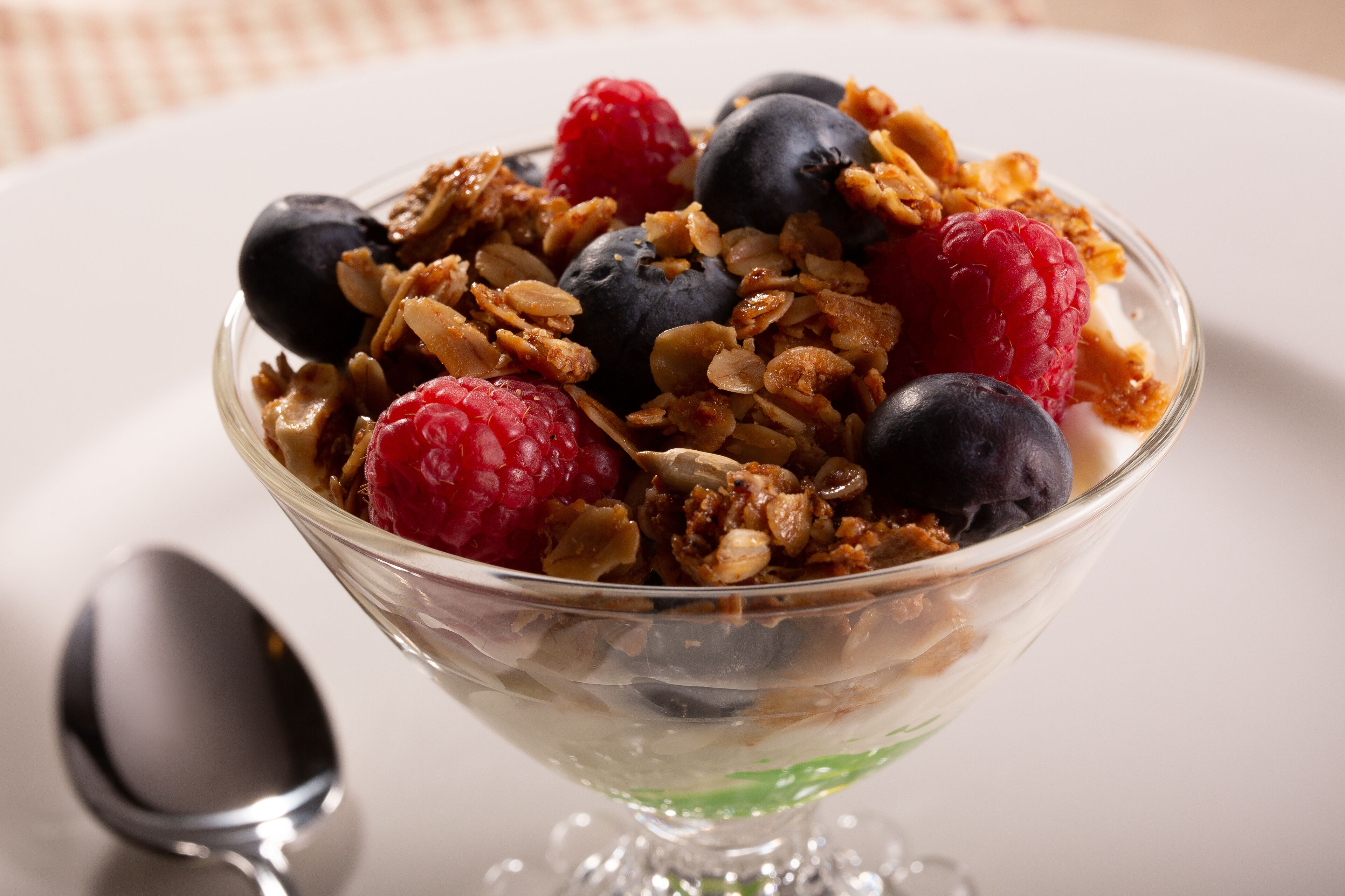 Un bol de yaourt agrémenté de granola et de fruits rouges.