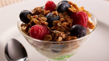 Un bol de yaourt agrémenté de granola et de fruits rouges.