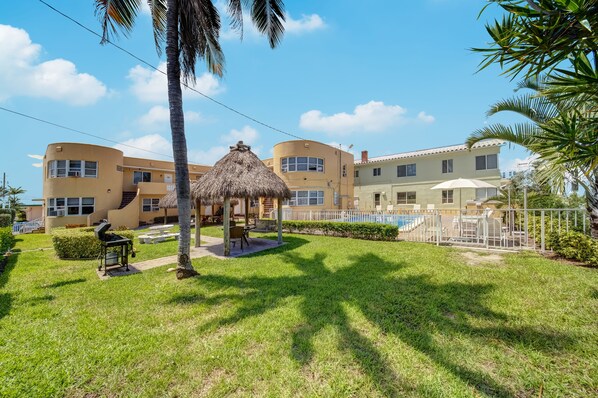 A resort with a pool, a thatched gazebo, and a well-maintained lawn. - Hollywood Beach Seaside (Hollywood)