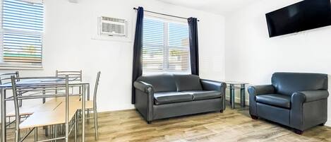 Un salon moderne comprenant un coin repas, un ventilateur de plafond et un téléviseur à écran plat fixé au mur.