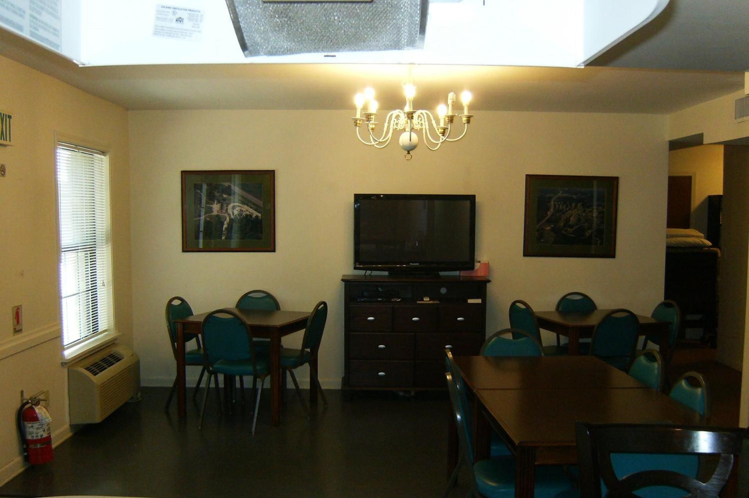 Un comedor con candelabro, televisión y obras de arte en las paredes.