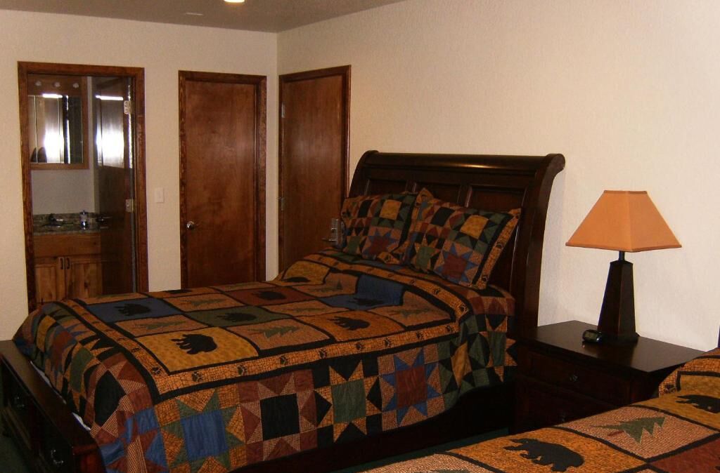 Un dormitorio con una cama de madera, una mesita de noche, una lámpara y un espejo.