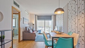 Een moderne woonkamer met een bank, eettafel, stoelen en een groot raam.