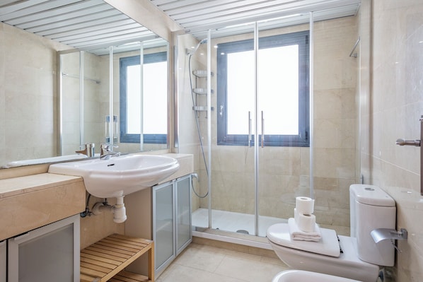 A modern bathroom with a large sink, a toilet, and a glass-enclosed shower.
