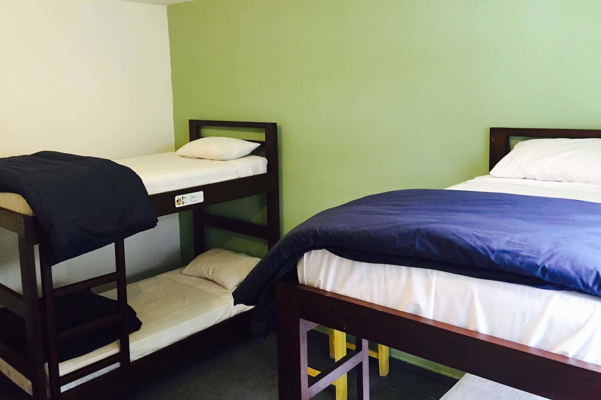 A bunk bed with a lower bunk and a single bed, both with white bedding and wooden frames.