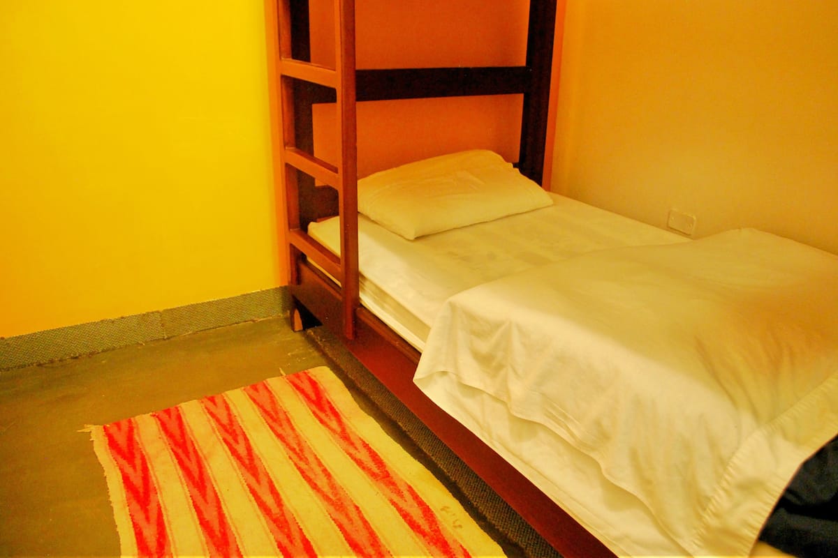 A bunk bed with white bedding in a room with yellow walls.