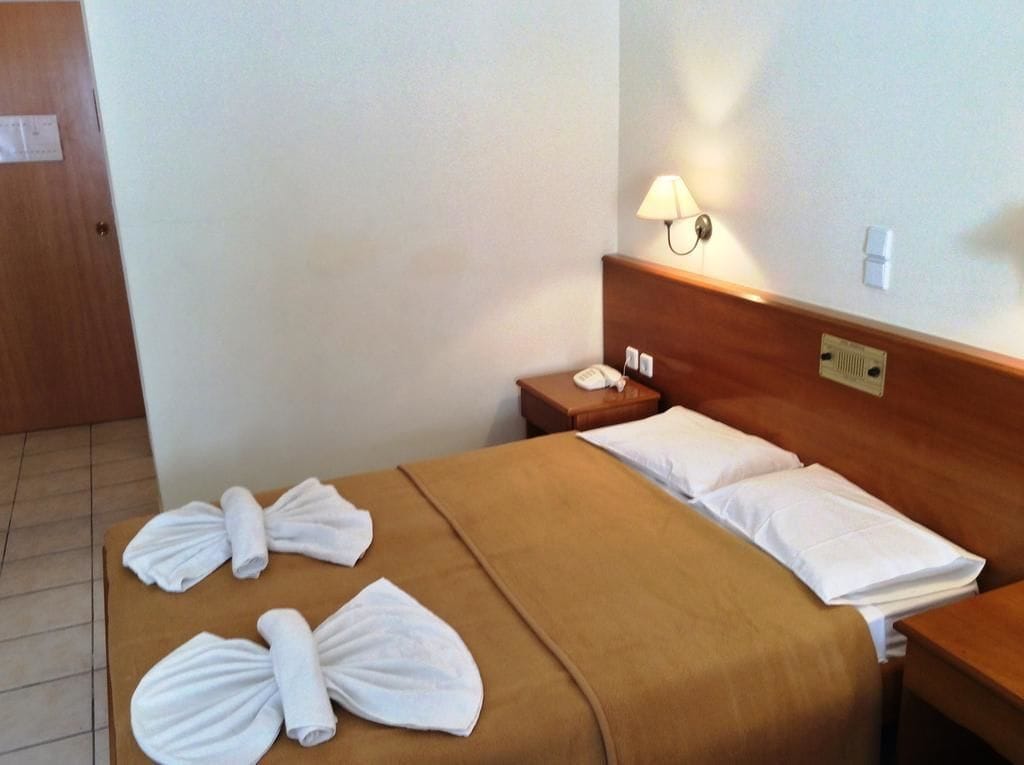 Una habitación de hotel con una cama, una mesita de noche, una lámpara y toallas sobre la cama.