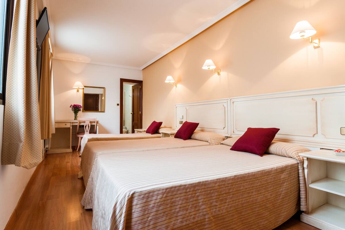 A hotel room with two beds, a desk, and a chair.