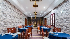 A restaurant with brick walls, blue tablecloths, and wooden chairs. - Victoria (Linares)