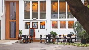 A cafe with outdoor seating, a wooden door, and large windows. - Grätzlhotel Belvedere (Vienna)