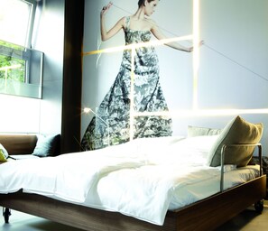 Een moderne slaapkamer met een groot bed, een nachtkastje en een tv aan de muur.