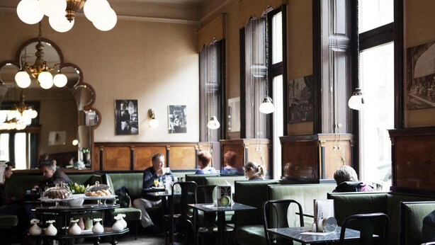 A restaurant interior with booths and tables, large windows, and hanging light fixtures. - Grätzlhotel Belvedere (Vienna)