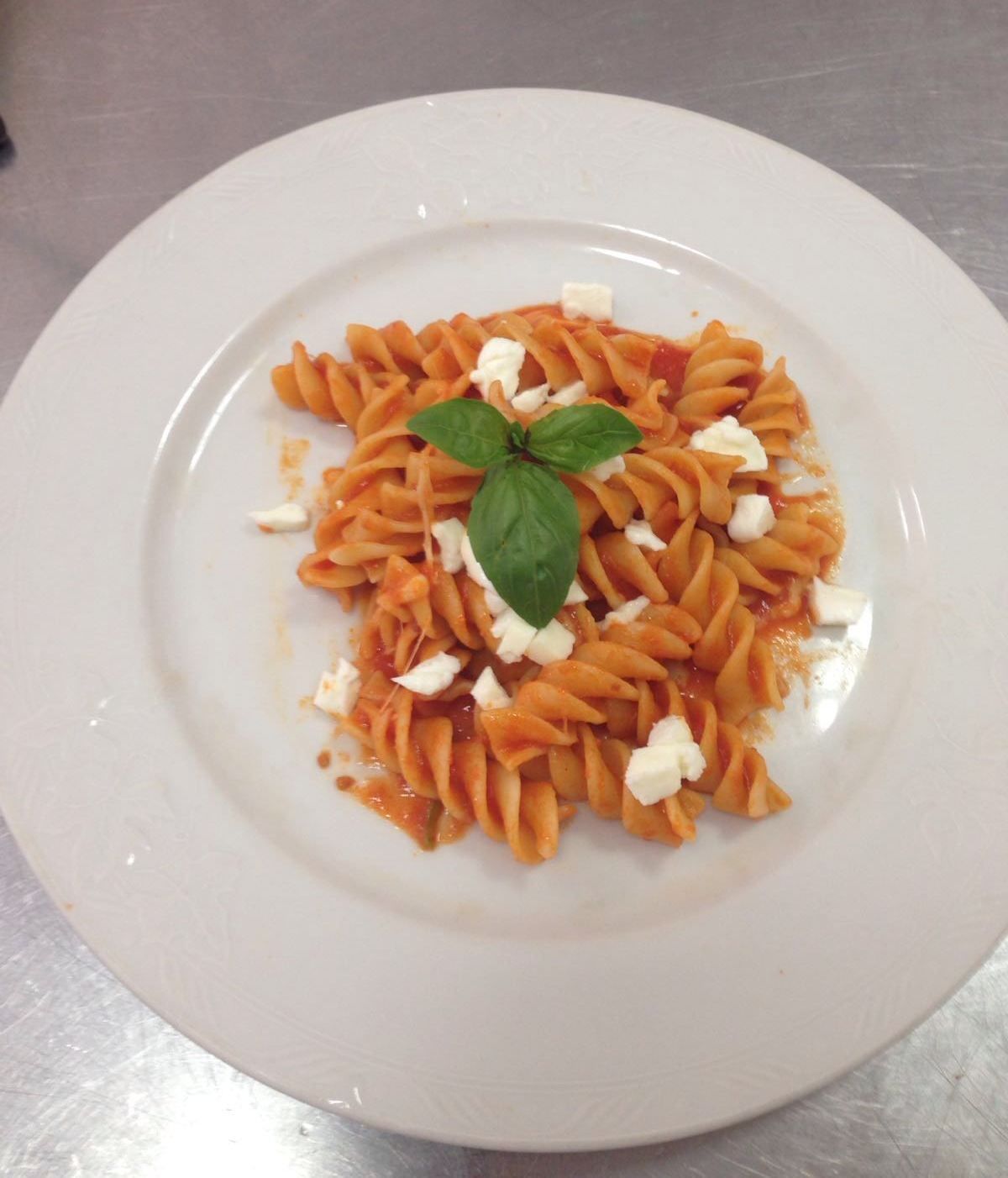 A plate of pasta with a basil leaf garnish.