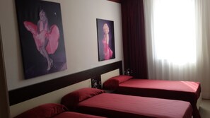 Una habitación de hotel con dos camas, un cabecero y dos cuadros en la pared.