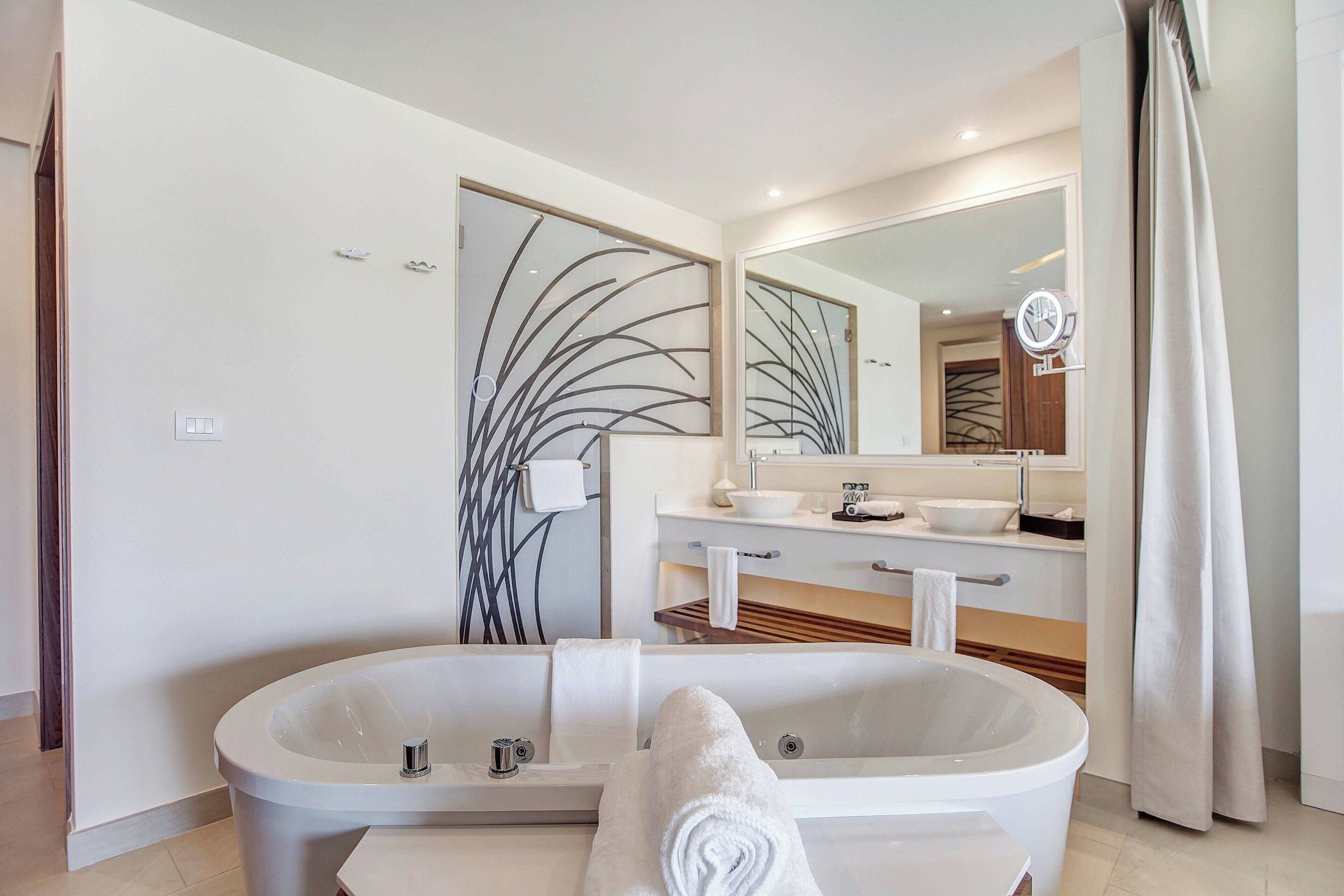Une salle de bain moderne avec une baignoire sur pieds, un grand miroir et un meuble-lavabo doté d’un évier et d’un porte-serviettes.