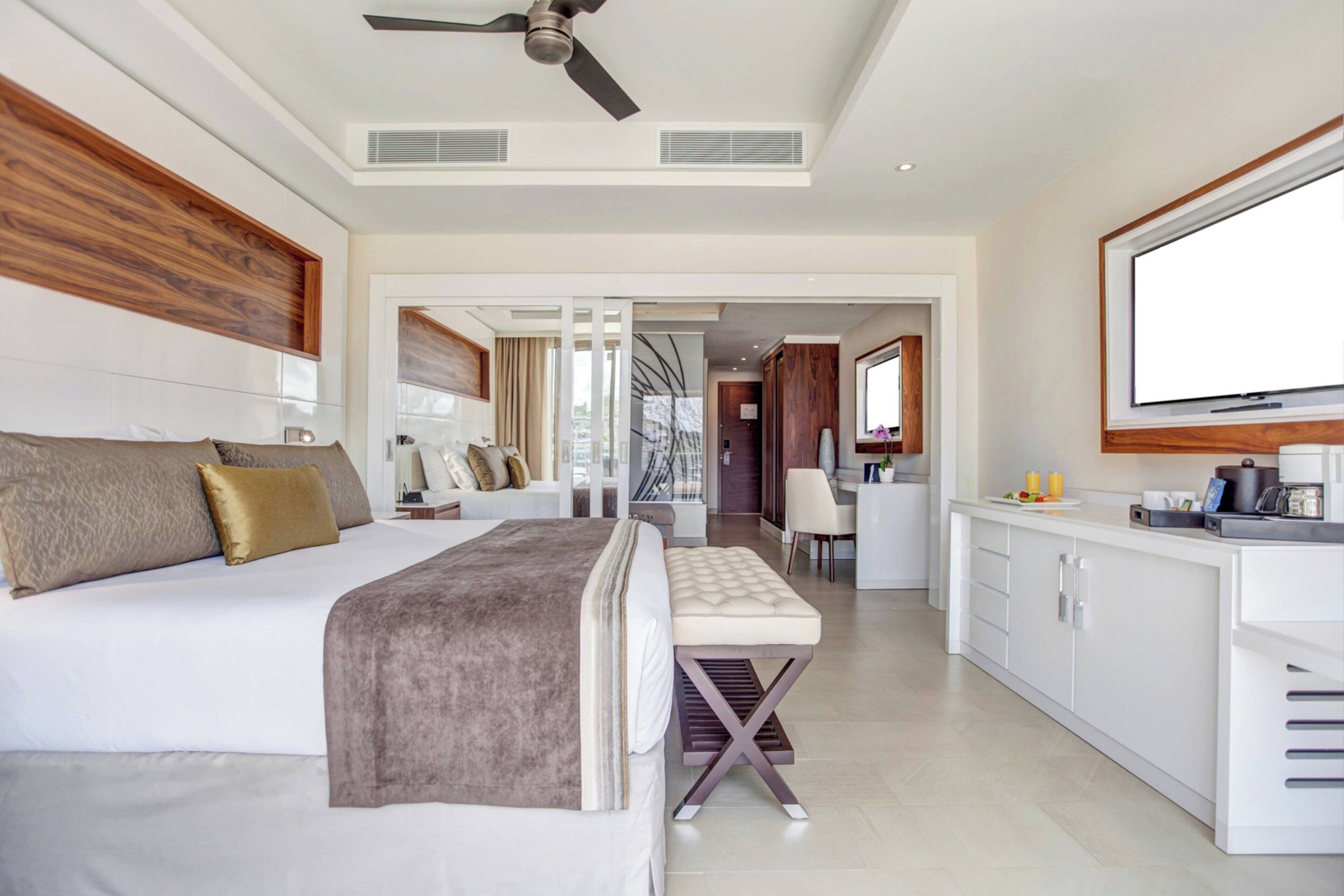 A modern hotel room with a large bed, a desk, and a television.