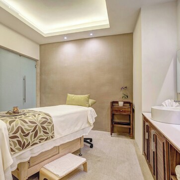 A modern bedroom with a bed, bedside table, and a bathroom with a sink and mirror.