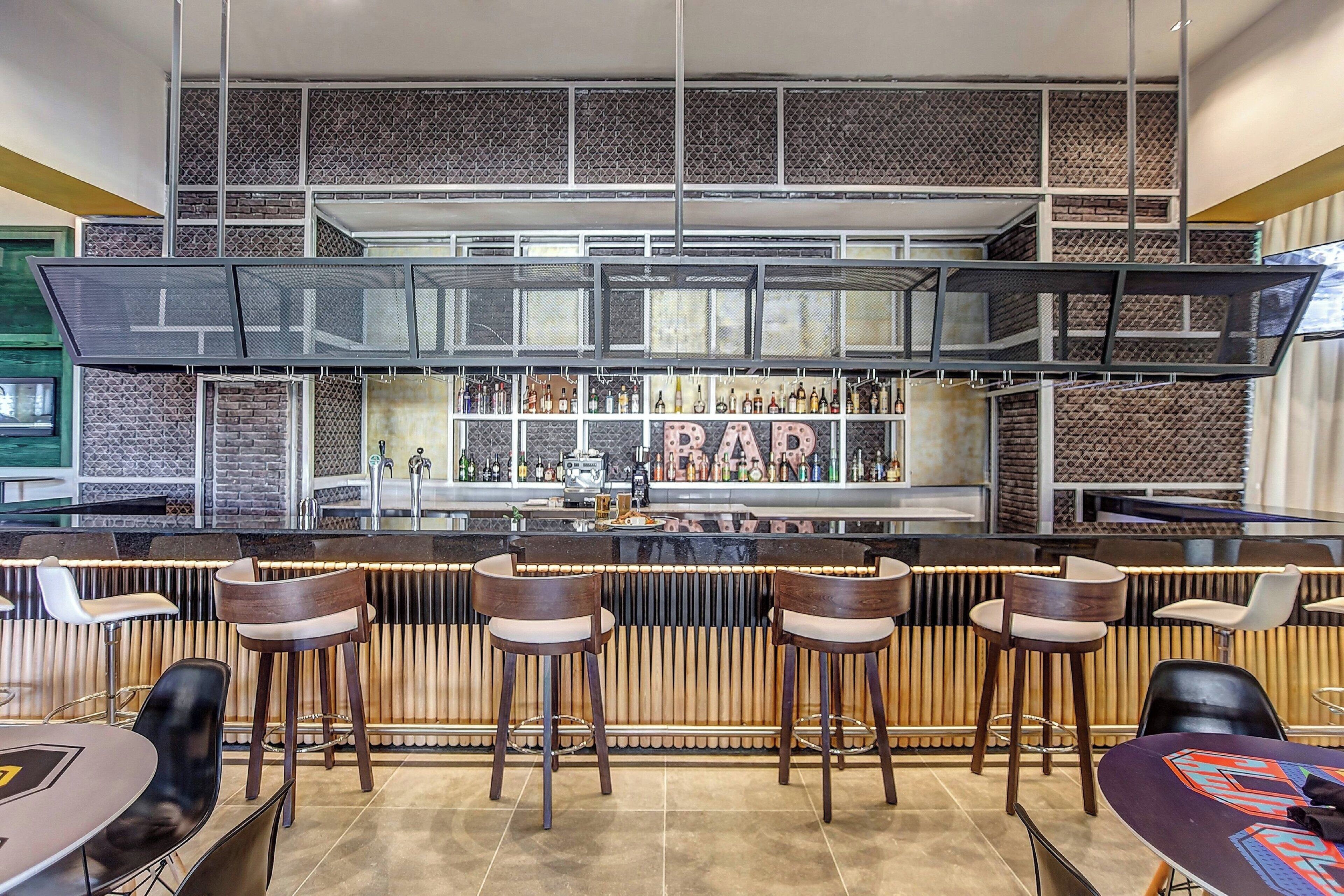 A bar area with multiple stools, a counter with bottles, and a wall with a 'BAR' sign.