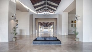 A spacious hallway with a high ceiling and a central staircase leading to a distant area.