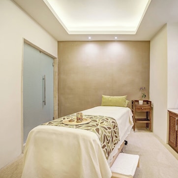A modern hotel room with a bed, bedside table, and a large mirror.