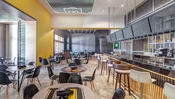 Un restaurante moderno con barra, diversas opciones de asientos, incluyendo mesas redondas y taburetes de bar, y una cocina a la vista.