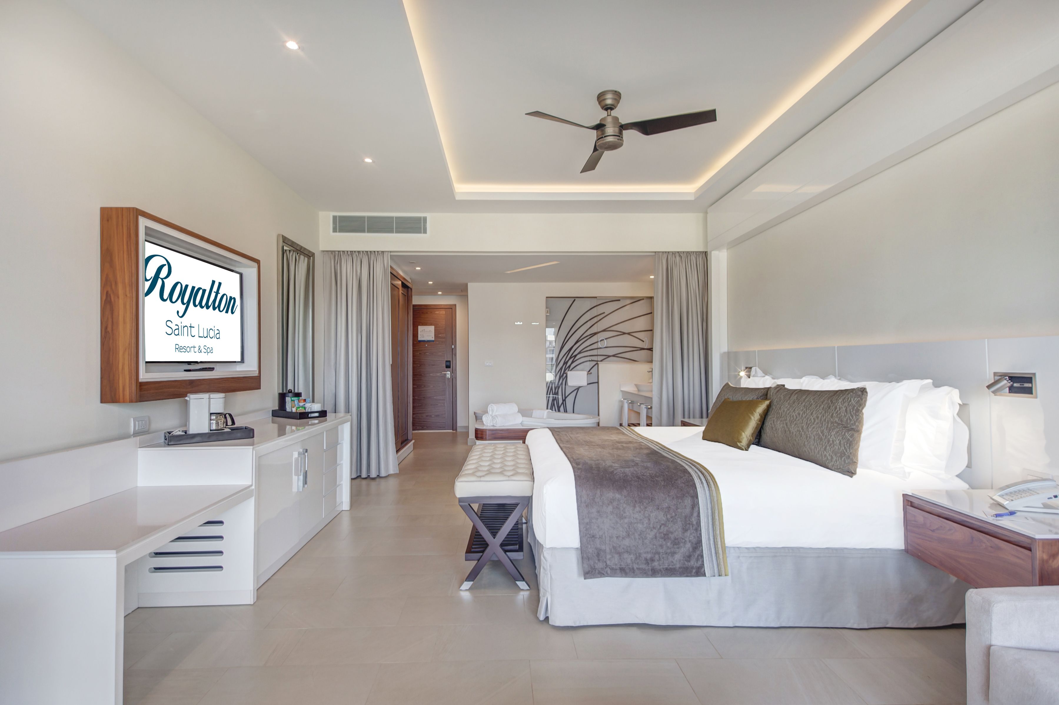 Une chambre d’hôtel moderne équipée d’un lit, d’une table de chevet et d’un téléviseur fixé au mur.