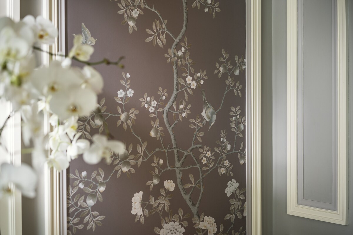 Un mur orné d’un motif floral et un chambranle de porte blanc.