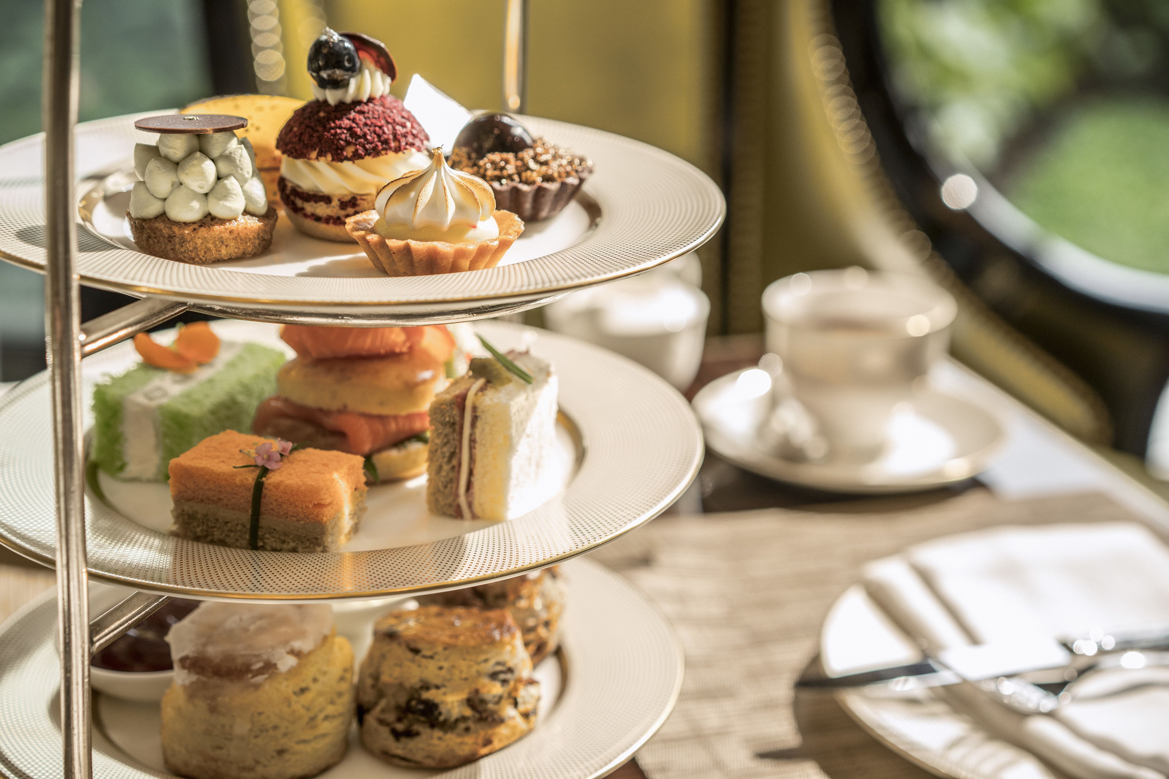 A three-tiered dessert stand with various pastries and cakes.
