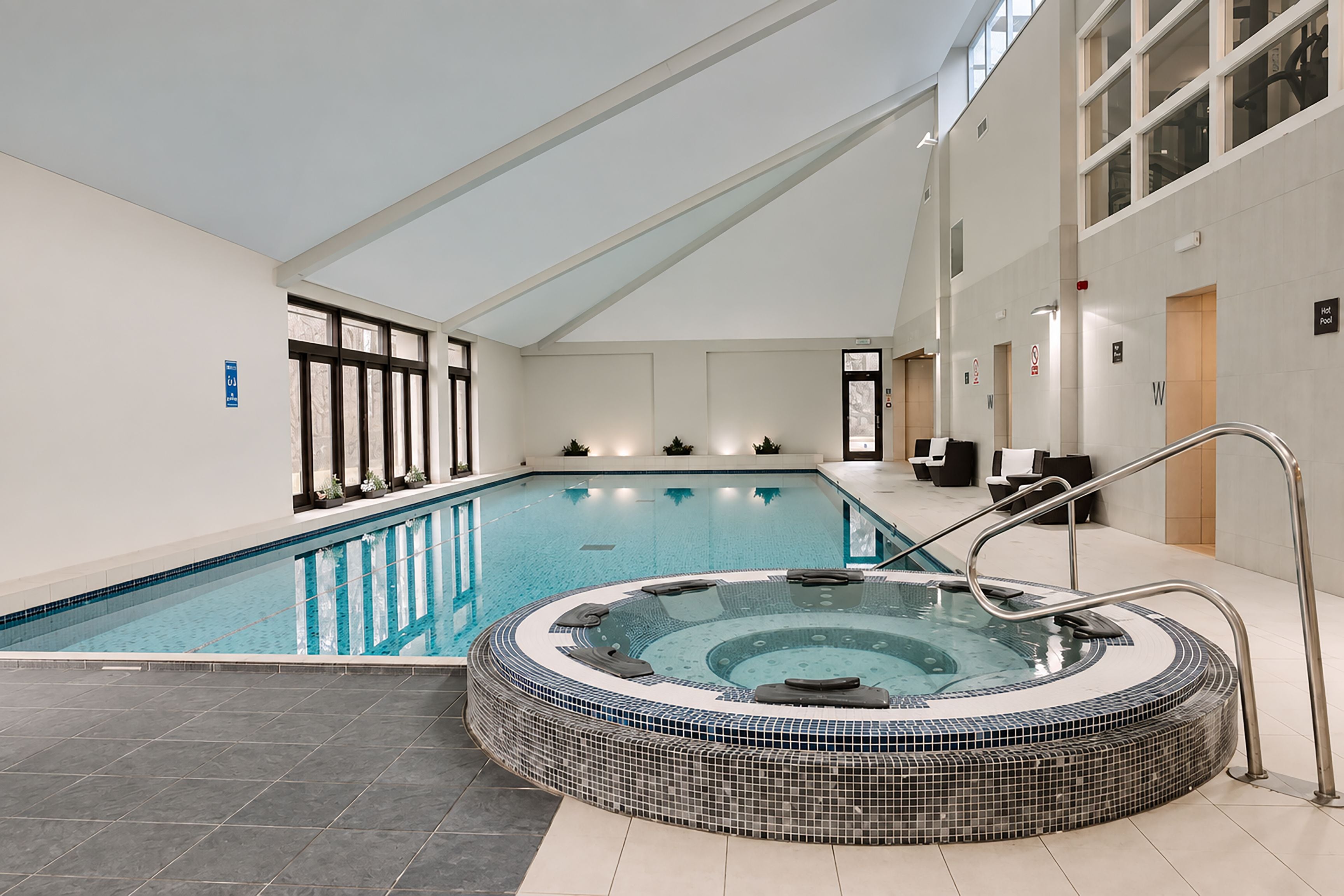 Ein Innenpool mit Whirlpool, klarem Wasser und gefliestem Boden.