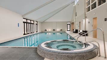 Ein Innenpool mit Whirlpool, klarem Wasser und gefliestem Boden.