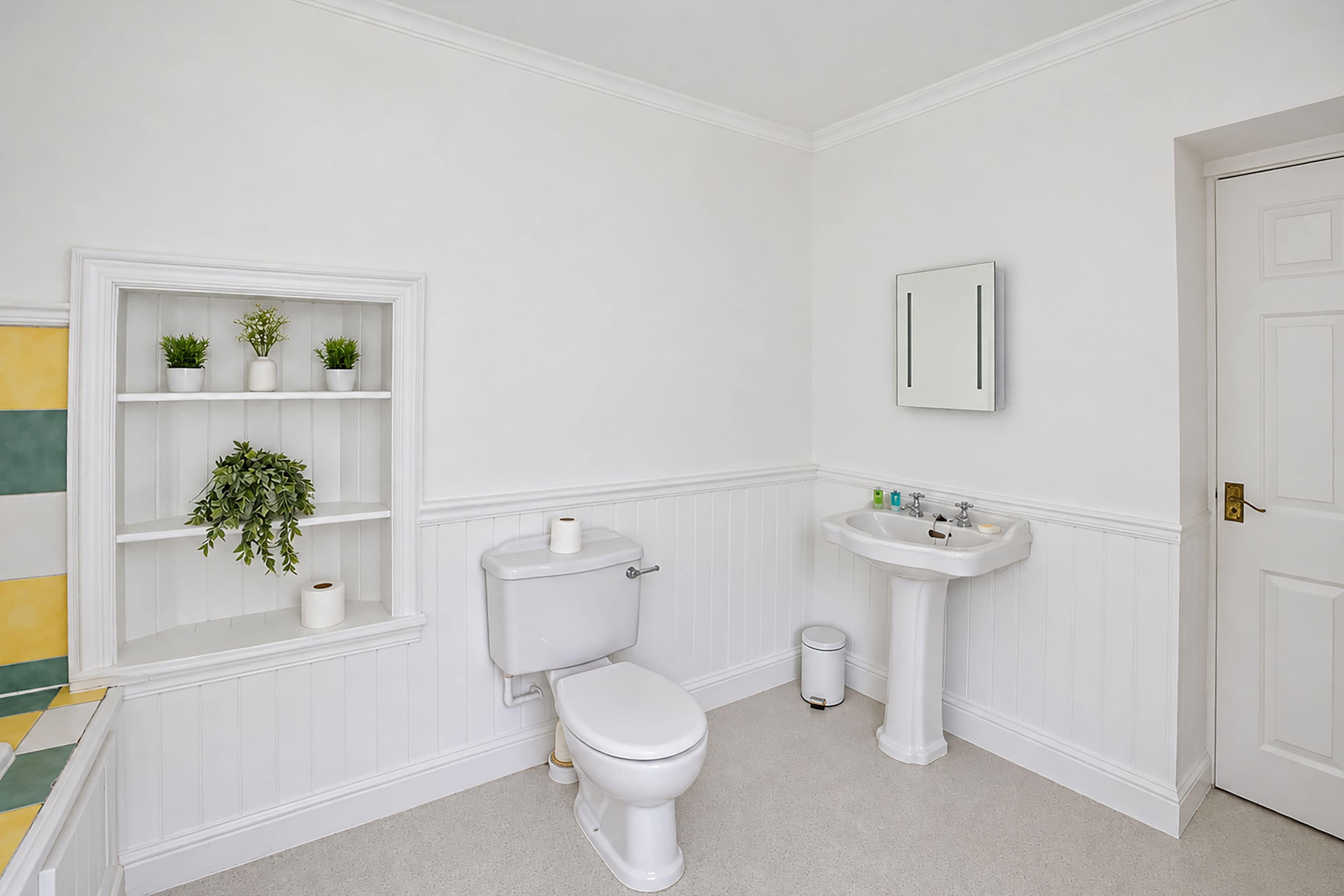 Une salle de bain avec des toilettes, un lavabo et des étagères ornées de plantes.