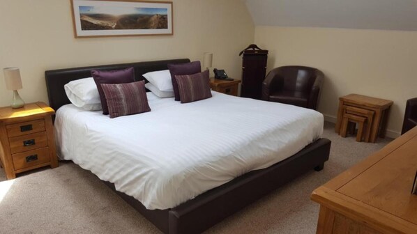 A bedroom with a large bed, bedside tables, a chair, and a desk.