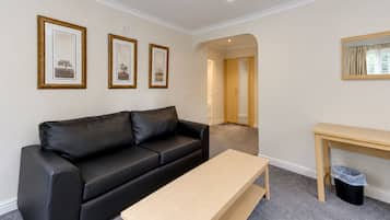 Une pièce avec un canapé en cuir noir, une table en bois et trois tableaux encadrés accrochés au mur.