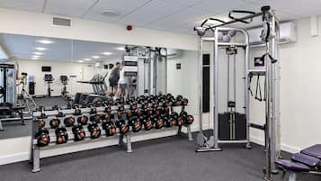 Et fitnessrum med træningsudstyr, en drikkefontæne og et spejl.