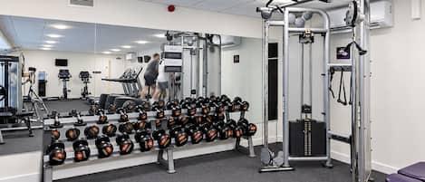 Une salle de sport équipée de matériel d’exercice, d’un distributeur d’eau et d’un miroir.