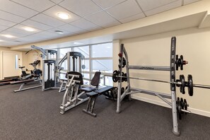 Een fitnessruimte met diverse trainingsapparaten, waaronder krachttoestellen en een bankdrukapparaat.