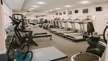 Un gimnasio con diversos equipos de ejercicio, incluyendo cintas de correr, elípticas y máquinas de pesas.