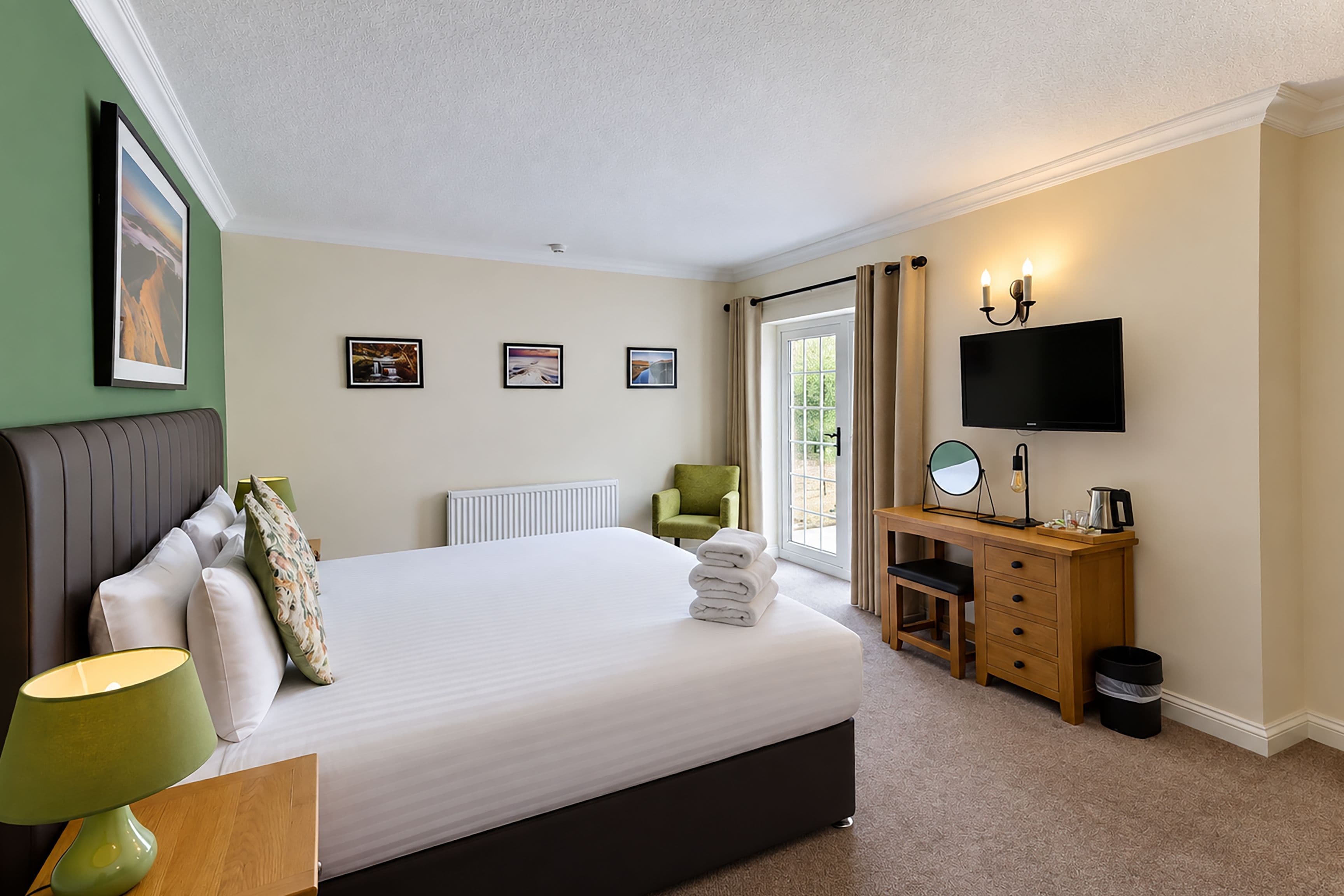 A hotel room with a bed, a desk, a chair, a TV, and a window with curtains.