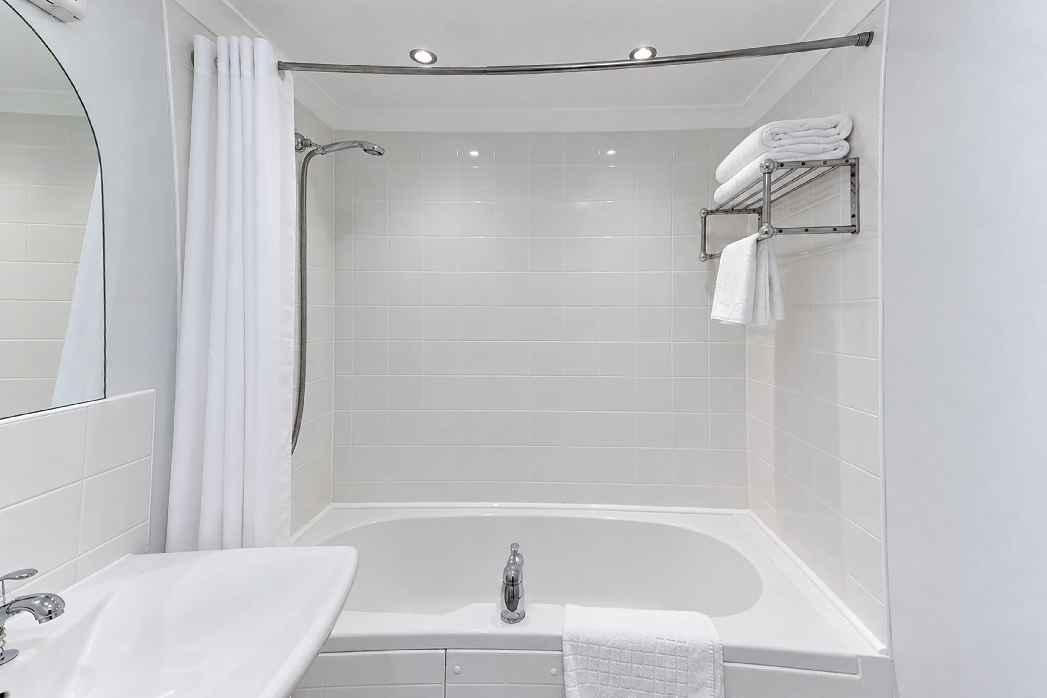 A modern bathroom with a freestanding bathtub, a showerhead, and a towel rack.