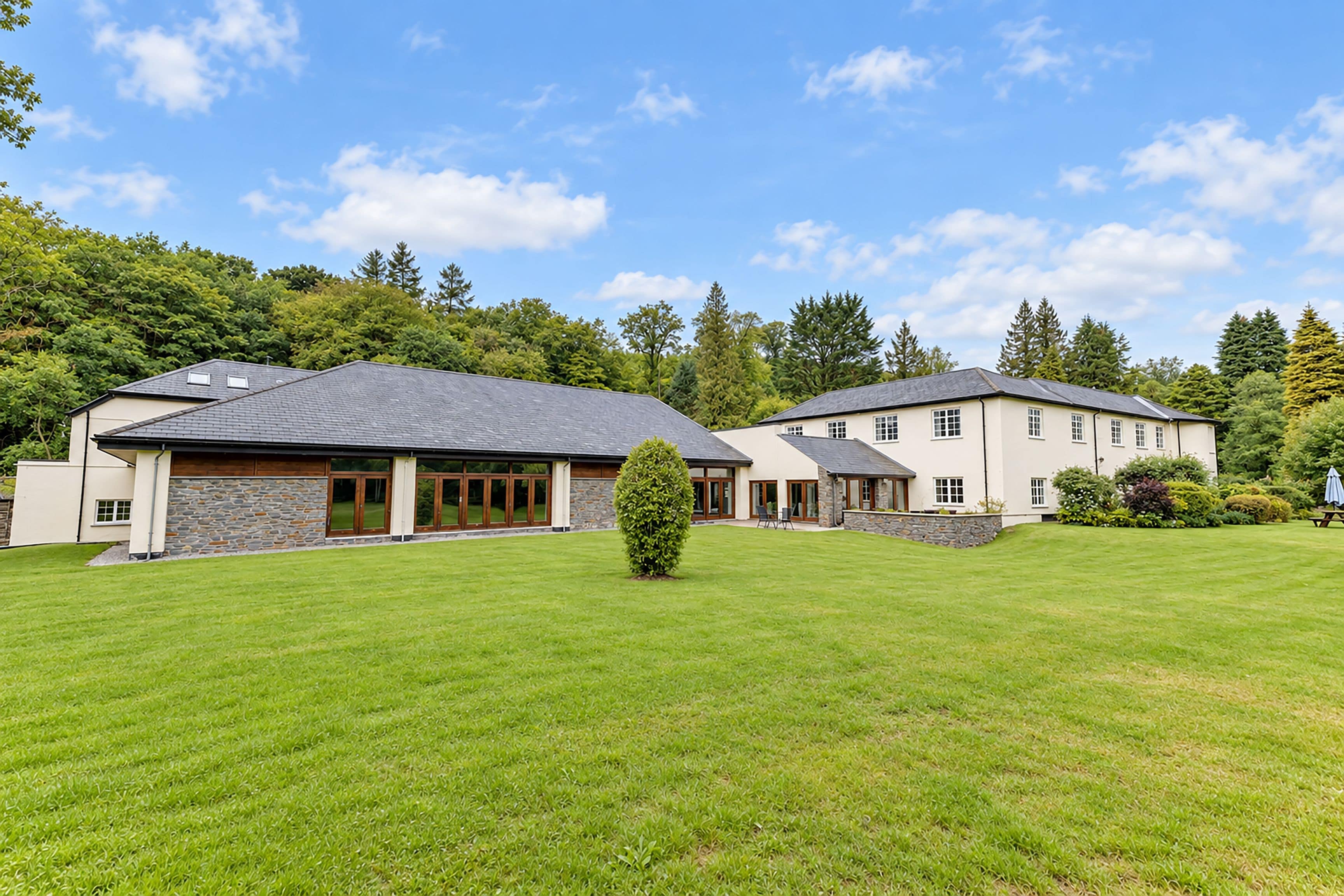A large, modern house with a spacious lawn and a well-maintained garden.