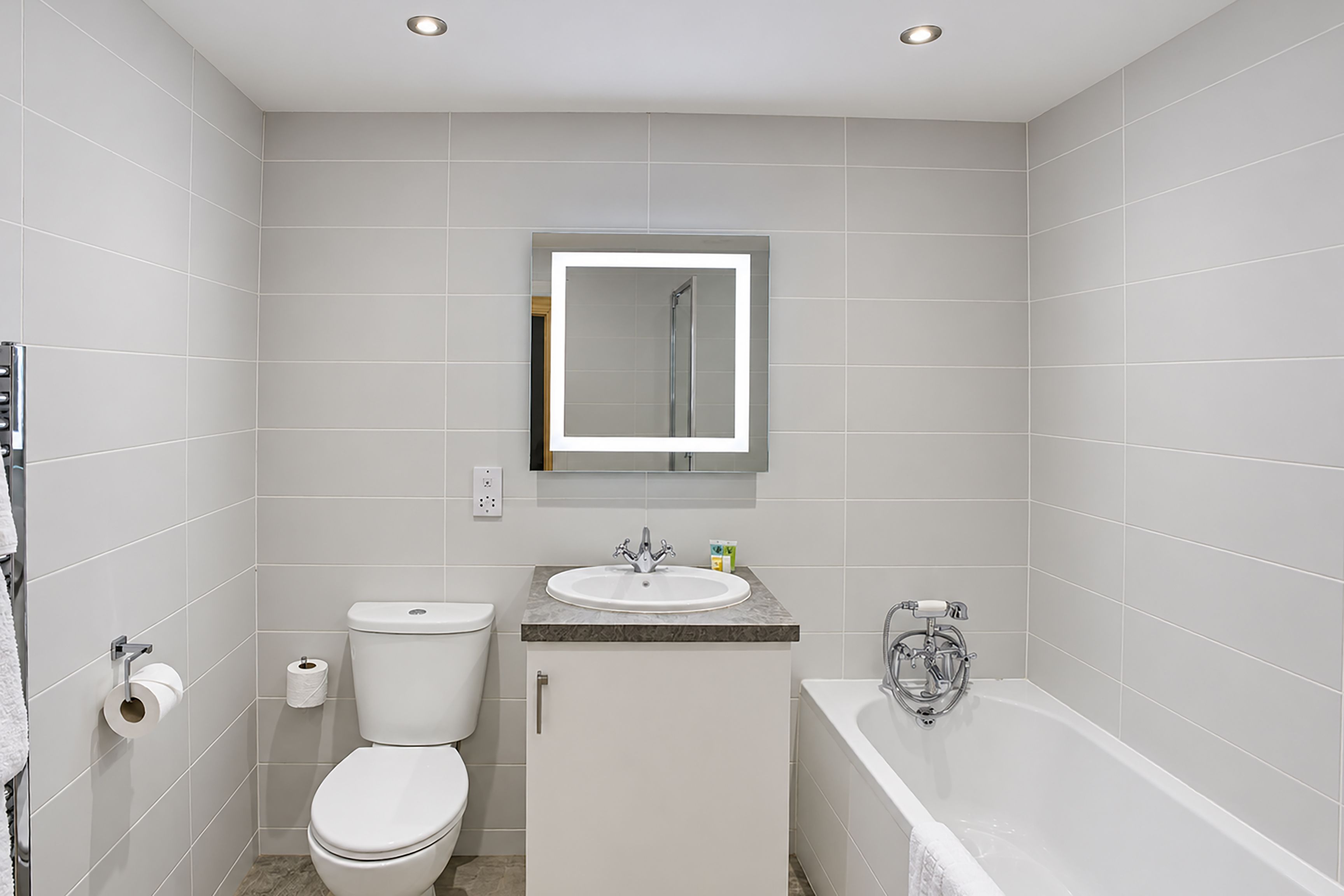 Une salle de bain comprenant des toilettes, un lavabo, un miroir et une baignoire.
