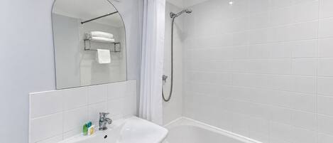 Un baño moderno con un lavamanos blanco, una bañera y una ducha.