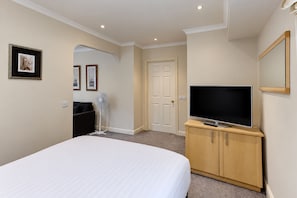 A hotel room with a bed, a television on a wooden cabinet, a door, and a wall-mounted picture. - Nant Ddu Lodge Hotel & Spa by Belvilla (Merthyr Tydfil)