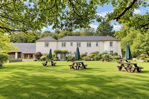 A large white building with a symmetrical facade, surrounded by a well-maintained lawn with picnic tables and umbrellas. - Nant Ddu Lodge Hotel & Spa by Belvilla (Merthyr Tydfil)