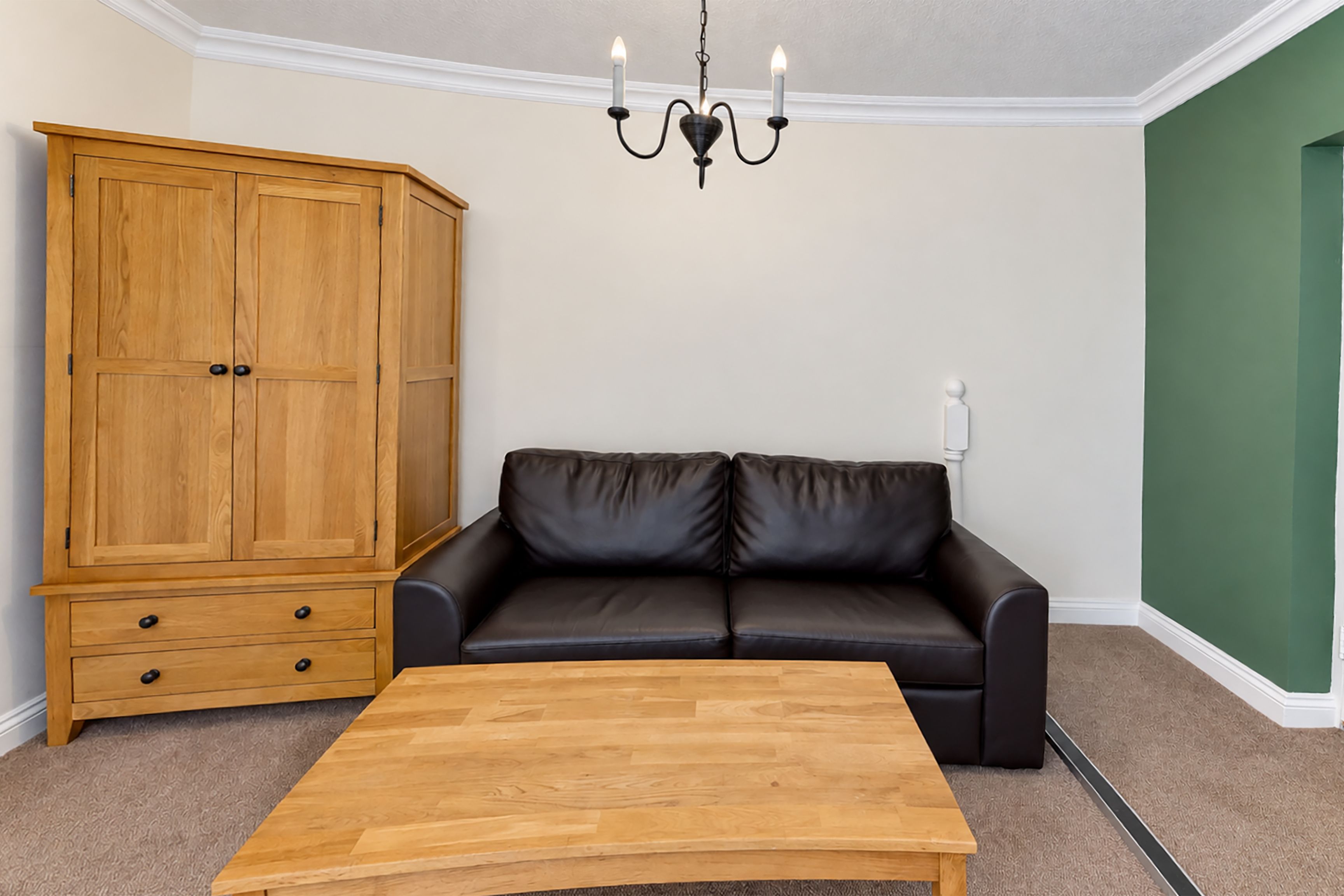Une pièce comprenant un meuble en bois, un canapé en cuir noir et une table basse en bois.
