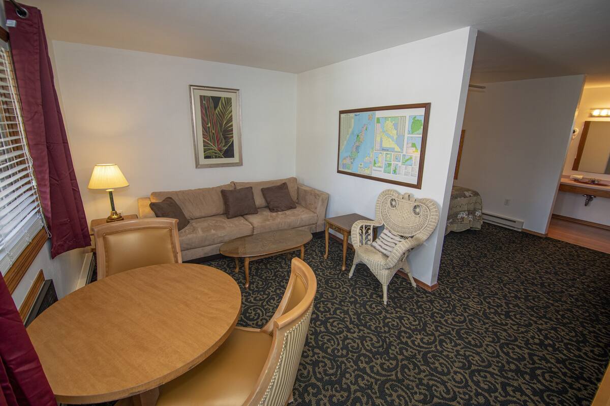 A living room with a sofa, a round table, and a patterned carpet.