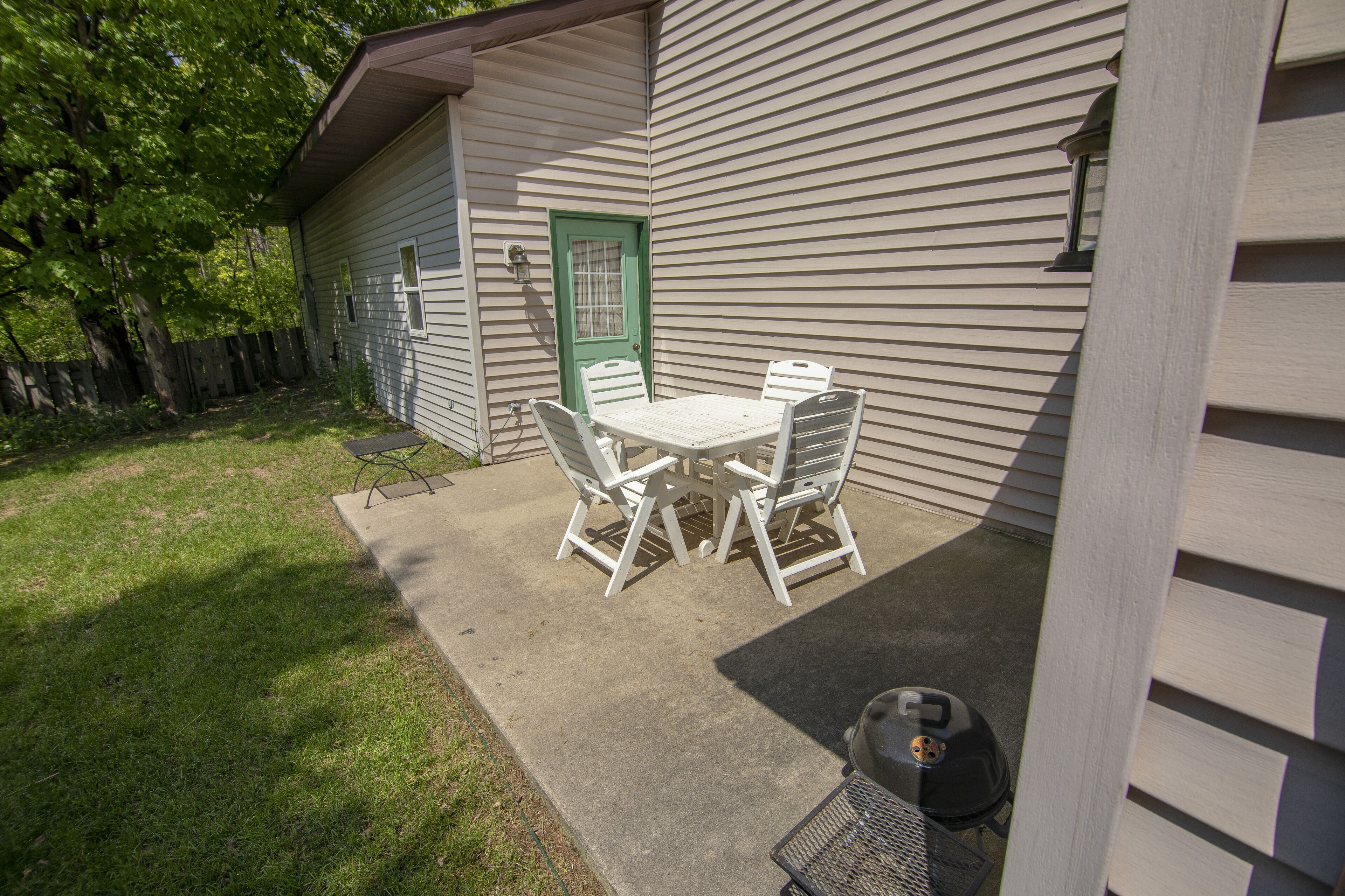 A patio with a table and chairs, a green door, and a barbecue grill.