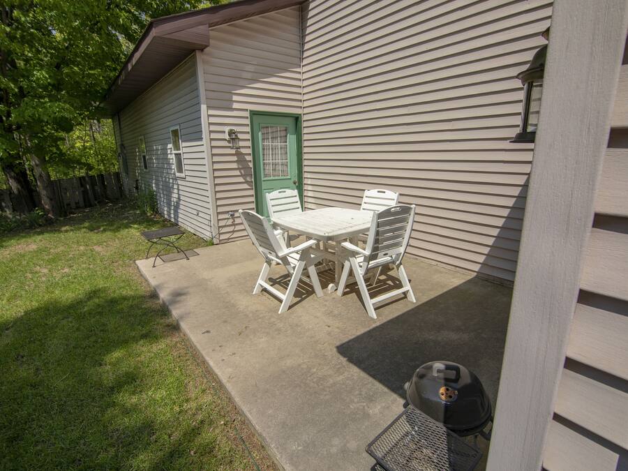 A patio with a table and chairs, a green door, and a barbecue grill.